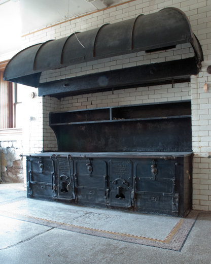 Kitchen Stove- During a weekend house party, Staatsburgh would have functioned much like a fine hotel. The Millses employed three French chefs to create extravagant menus for their guests. The coal stove and the coal furnaces would have been fired up by the night watchman before he went off duty in the early morning, and used throughout the day under the watchful eye of the head chef. The chef supervising the under chefs, kitchen maids, and scullery maids would have juggled the preparation of breakfast, lunch, and dinner in order to perfectly time presentation to the family and guests. One of the under chefs, assisted by the kitchen maids, probably made the meals for the servants. The stove is a French range made by Duparquet, Hout & Moneuse Co., a premier supplier of commercial stoves in the mid-to late 19th and early 20th centuries. This stove was patented on November 19, 1907.